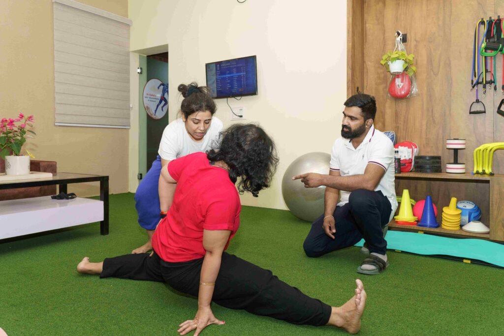A yoga instructor assisting a woman with deep stretching at Dr. Kanhaiya’s Yoga and Physiotherapy Center in Indore